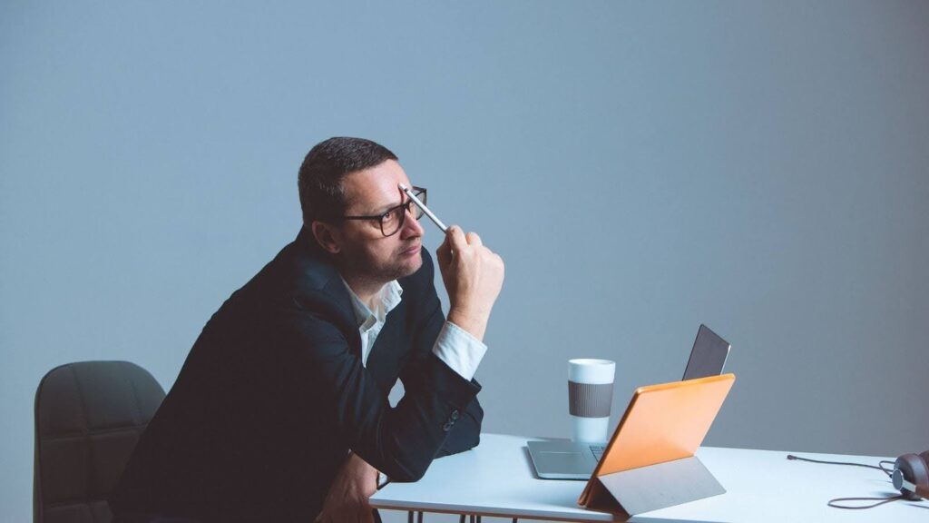 Office worker at desk with pen and tablet thinking sternly