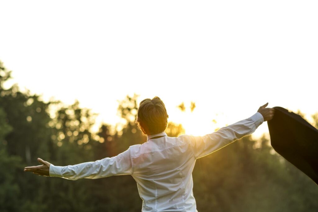 businessman-with-arms-out-looking-optimisitc-at-sun